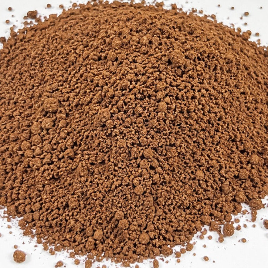 A mound of fine brown coffee grounds photographed from above on a plain white background.