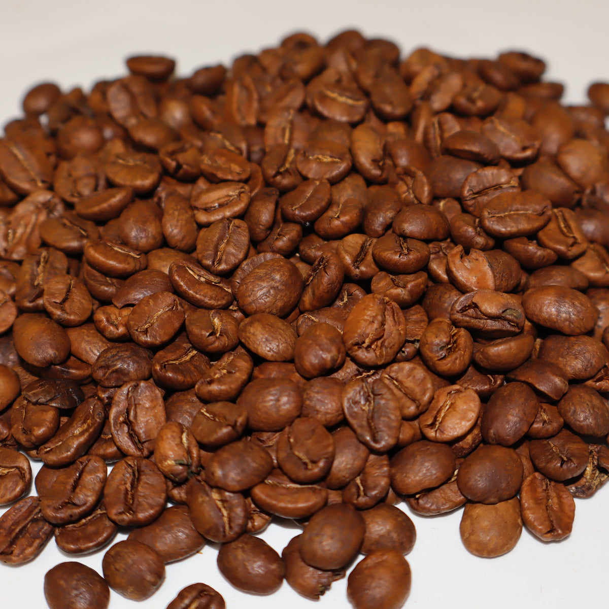 Pile of roasted coffee beans on a white background