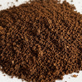 A small mound of dark brown ground coffee powder on a plain white background.